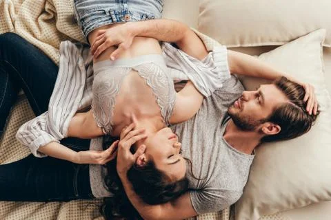 High angle view of beautiful young couple in love hugging while lying on bed Stock Photos