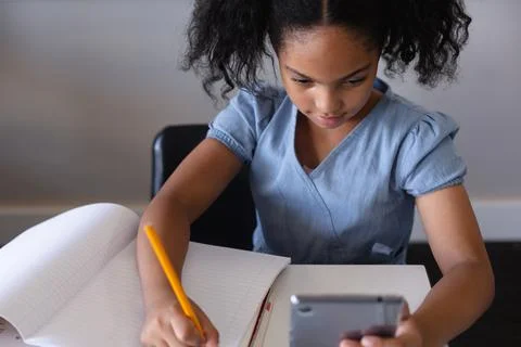 High angle view of biracial elementary schoolgirl using digital tablet while 写真素材