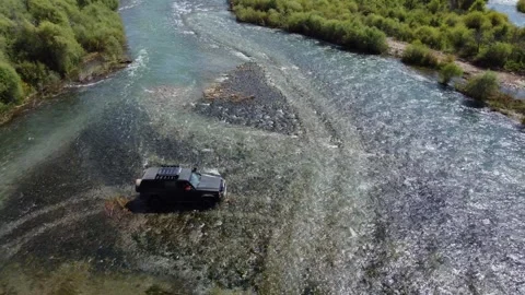 High angle view of black 4x4 off-road vehicle crossing wide mountain river Stock Footage 335080806