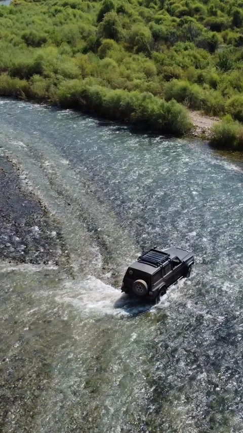 High angle view of black 4x4 off-road vehicle driving through mountain river Stock Footage 336690849