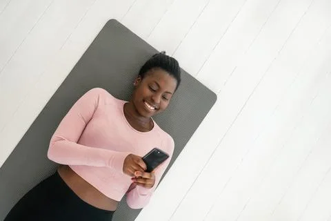 High angle view Black African woman relaxing on yoga mat, smiling looking at  Fotos Stock