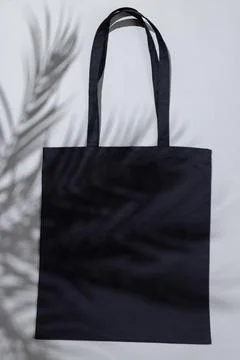 High angle view of black canvas bag with copy space and leaf shadow on grey 스톡 사진