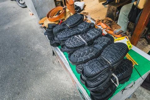 High angle view of black rubber shoe outsoles and leather belts on a cobble.. 库存照片