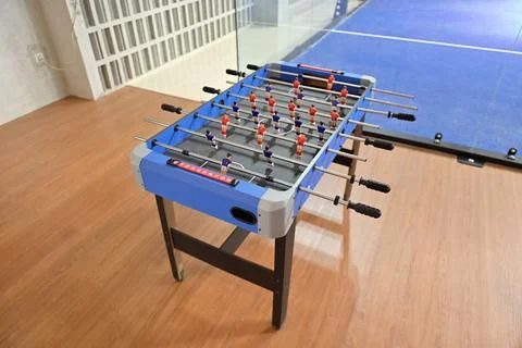 High-angle view of a blue foosball table positioned on a wooden floor near .. Stock Photos