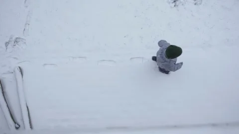 High angle view boy child gray overalls pure white snow kid leaves footprints Video stock 261610493