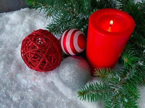 High angle view of burning red candle, Christmas baubles with fir tree on snow Foto stock