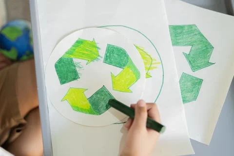 High angle view of child hand with coloring recycling symbol with green cra.. Stock Photos