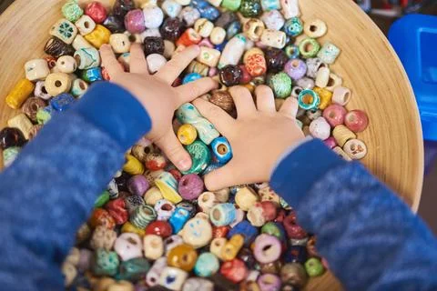 High angle view of a child's hands digging through a bowl filled with colorfu 스톡 사진