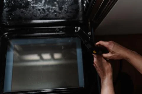 High-angle view of cleaner person sanitizing black gas oven interior with high Stock-Fotos