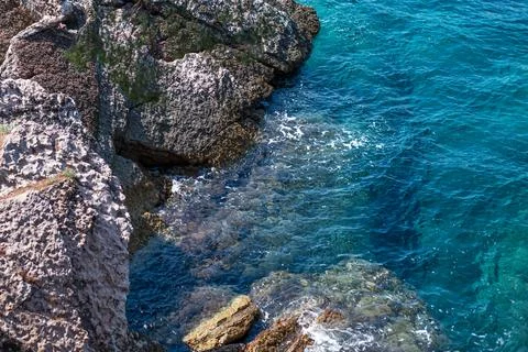 High-angle view of clear turquoise seawater on rugged rocky shoreline Фото