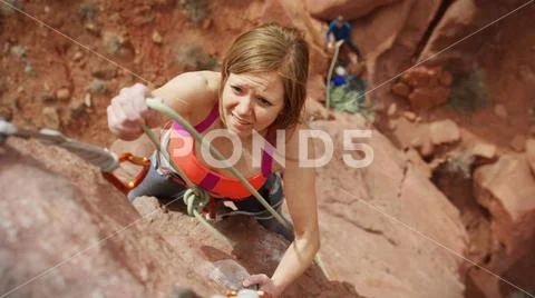 High angle view of climber tying cord on carabiner on steep rock cliff Stock Photos