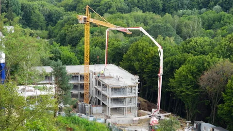 High-angle view of a concrete pump truck and yellow tower crane. Stock Footage 342764741