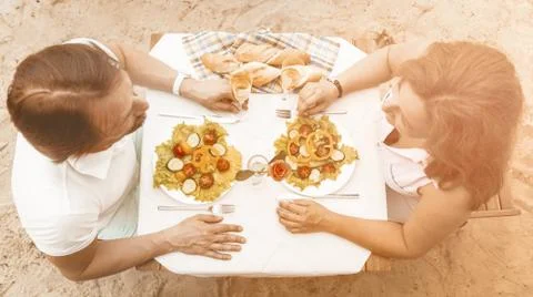 High angle view couple in love sitting at a table on a sandy beach Stock Photos