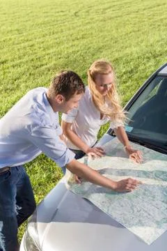 High angle view of couple reading map on car hood during road trip Fotos Stock