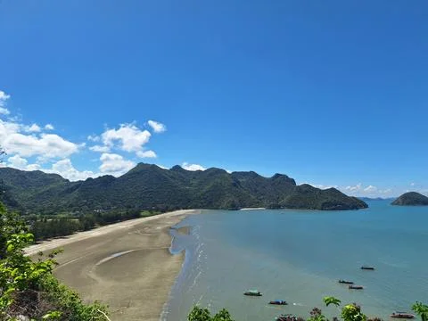 High angle view of a curved bay with low tide sand flats and forested hills Stock Photos