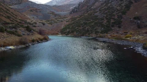 High angle view of dark mountain lake surrounded by autumn hills and rocky slope Video stock 334326697
