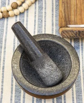 High angle view of dark stone mortar and pestle on striped fabric table run.. Stock Photos