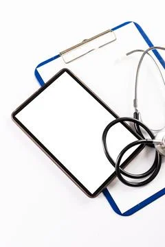 High angle view of digital tablet with stethoscope and clipboard on white Stock Photos