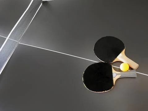 High angle view of dilapidated table tennis bat and ball on dark color table Stock Photos