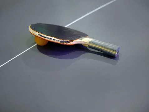 High angle view of dilapidated table tennis bat and ball on dark color table Stock Photos