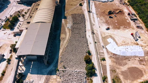 High angle view of a factory warehouse and raw materials.. A long building sits Stock Footage 340283955