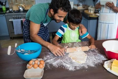 High angle view father assisting son for rolling dough Stock-Fotos