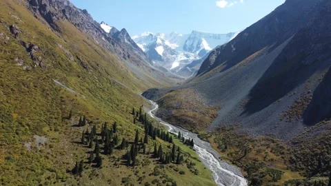 High angle view flying over deep glacial valley with winding river and peaks Stock Footage 335647190