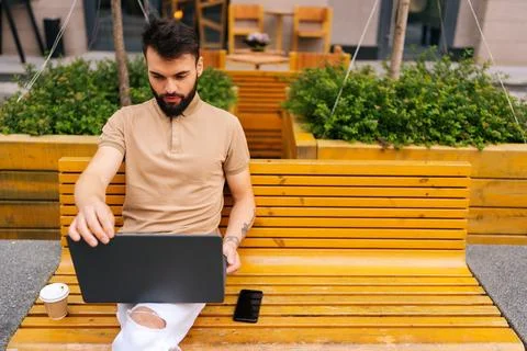 High-angle view of focused bearded young man remote working on laptop computer Stock Photos