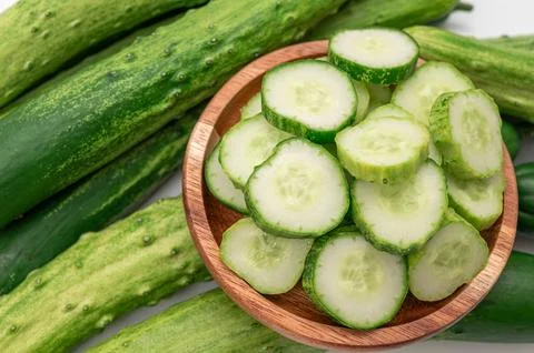High angle view of fresh cucumber slices in a wooden bowl with whole cucumber Stock Photos