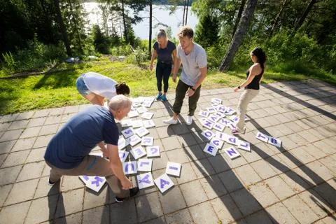 High Angle View Of Friends Solving Crossword Puzzle On Patio Stock Photos