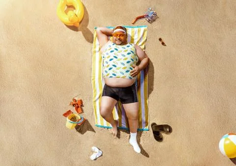 High angle view of funny overweight tourist resting on the beach Stock Photos