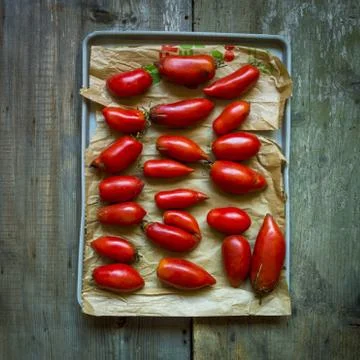 A high angle view of grape tomatoes on a tray on the wooden table under the l Stock Photos