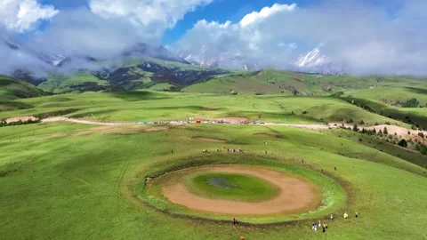 High Angle View of Green Mountain Plateau with Visitors and Distant Snowy Peaks Stock Footage 346334683