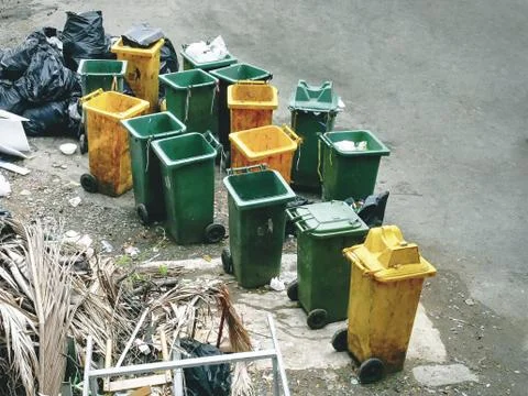 High Angle View of Group of Garbage Bins and Pile of Black Plastic Bags Foto stock