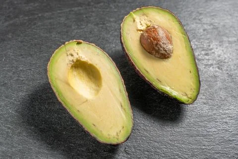 High angle view of halved avocado with brown pit on slate 库存照片