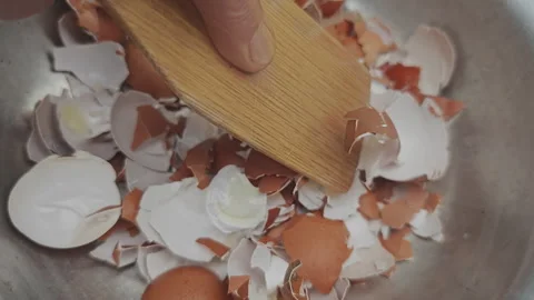 High angle view of a hand crushing brown eggshells with a wooden spatula Stock Footage 342276863