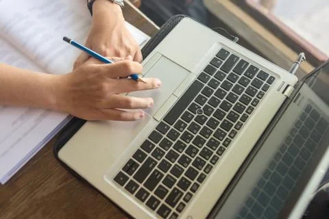 High angle view of hand holding pen while using laptop Stock Photos