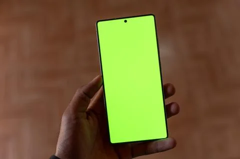 High Angle View of Hand Holding Smartphone with Green Screen Mockup. Stock Photos
