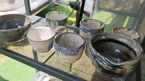 High angle view of handmade ceramic cups and bowls on a shelf. Stock Footage 340506823