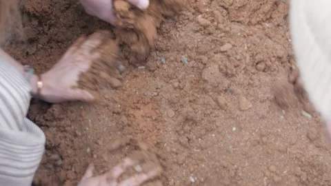 High angle view of hands removing red construction sand and adding water. 스톡 동영상 241841458