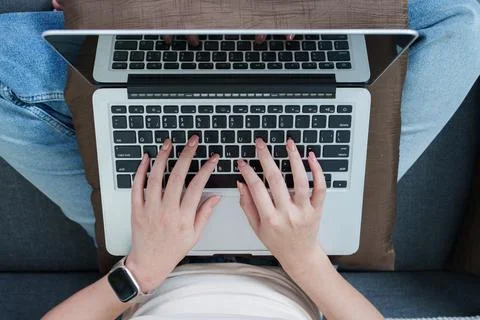 High angle view of hands typing on laptop computer on lap Stock Photos