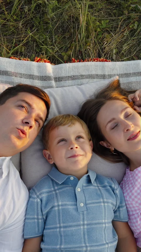 High angle view of happy family lying on picnic blanket and looking up Stock Footage 345725512