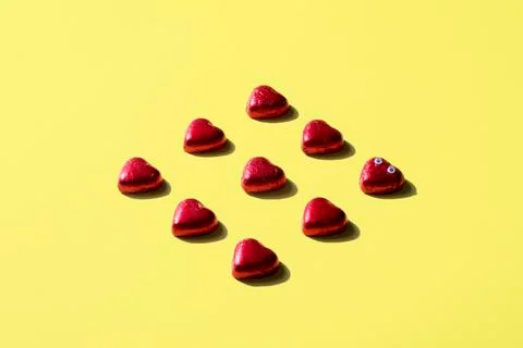 High angle view of heart shape chocolates wrapped in red foil over yellow Fotos de archivo