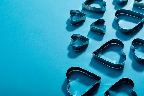 High angle view of heart shape pastry cutters with shadows by copy space on blue Fotos de archivo