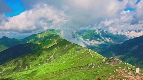 High angle view of hikers on a lush green mountain ridge and alpine valley 動画素材 345722672