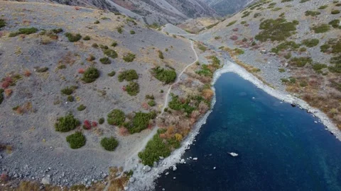 High angle view of hiking trail along shore of deep blue mountain lake Vidéo 334326872