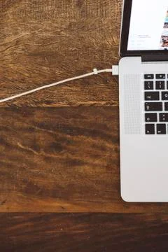 High angle view of laptop computer with USB cable on wooden table Fotos Stock
