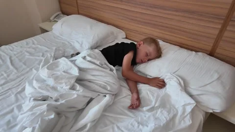 High angle view of a little boy sleeping alone in the middle of a large double Stock Footage 335361070