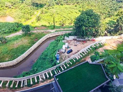 High-angle view looking down at a winding concrete canal bordering a lush g.. Stock Photos