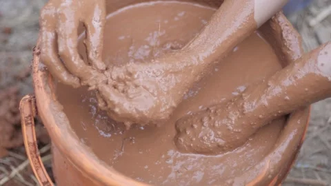High angle view of male hands and arms mixing clay with water in a bucket 스톡 동영상 241841354